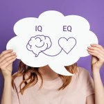 iq eq concept. girl holding speech bubble poster with hand drawing a brain and heart. IQ intelligence quotient and EQ emotional intelligence concept
