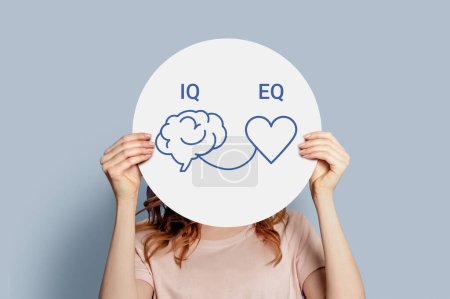 iq eq concept. girl holding poster with hand drawing a brain and heart. IQ intelligence quotient and EQ emotional intelligence concept