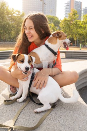 Foto de Lindo abrazo con adorable Jack Russell terriers perro, El joven mirando a la cámara. Vacaciones de verano. Ropa de color naranja brillante. Amar y confiar dueño de mascotas - Imagen libre de derechos