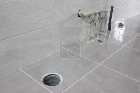 Téléchargez les photos : Tuyaux d'eau et d'égout dans la nouvelle salle de bain. Un endroit pour installer la plomberie - en image libre de droit