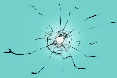 Foto de Vidrio roto sobre fondo azul. Un agujero de bala y grietas en la ventana - Imagen libre de derechos