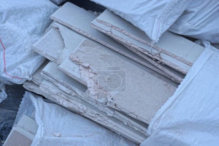 Foto de Piezas grises de paneles de yeso viejos en una bolsa blanca en la calle - Imagen libre de derechos