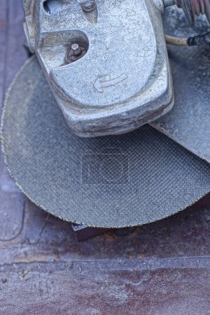 Foto de Parte de una gran amoladora eléctrica gris con un disco de corte se encuentra en una mesa marrón - Imagen libre de derechos