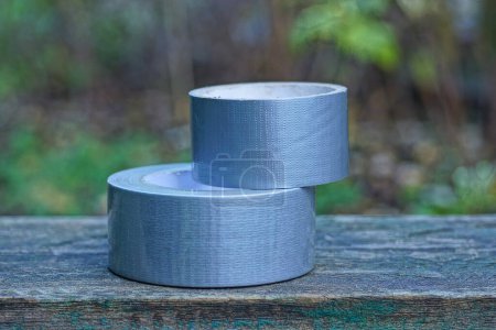 Foto de Dos madejas de cinta gris reforzada yacen en una mesa de madera en la calle - Imagen libre de derechos