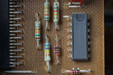 Téléchargez les photos : Partie d'un vieux circuit électronique brun avec un transistor noir et des diodes colorées - en image libre de droit