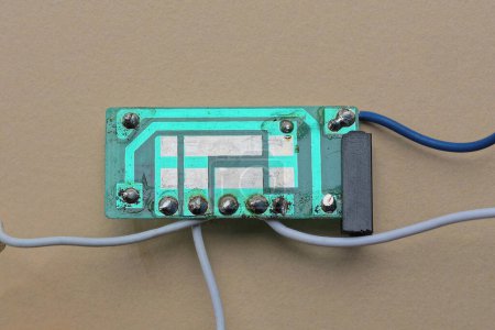 Photo for One green gray old plastic microcircuit with lead soldering with wires lies on a brown table - Royalty Free Image