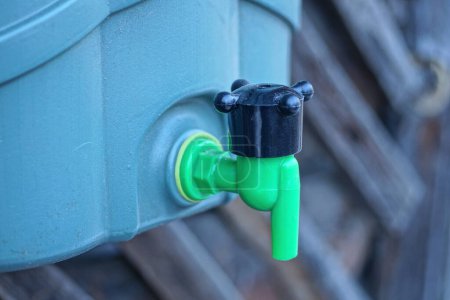 un robinet d'eau en plastique noir vert sur un réservoir à l'extérieur