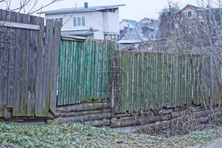 Foto de Old gray green wooden fence from boards on the street in grass - Imagen libre de derechos