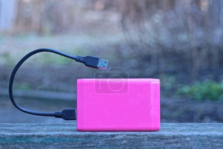 Photo for One pink plastic drive and a black usb cable stands on a gray table in the street - Royalty Free Image