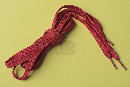 Photo for One skein of red laces lies on a yellow table - Royalty Free Image