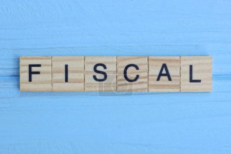 palabra fiscal hecha de letras grises de madera se encuentra en una mesa de madera azul