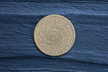 Photo for One old german brown five pfennig coin lies on a black wooden table - Royalty Free Image