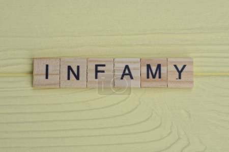 Photo for The word infamy of gray small wooden letters lies on a yellow wooden table - Royalty Free Image