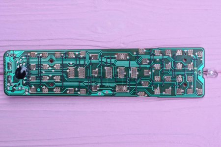 one green old long plastic microcircuit with lead soldering lies on a pink table
