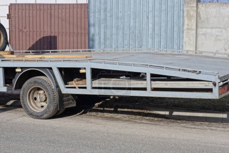 part of one tow truck with empty platform trailer on the street on the road