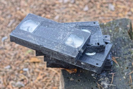 a pile of old black dirty videotapes lie on a gray table on the street