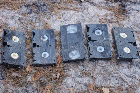 Foto de Una pila de cinco casetes de vídeo viejos y sucios de plástico negro se encuentran en el suelo gris en la calle - Imagen libre de derechos