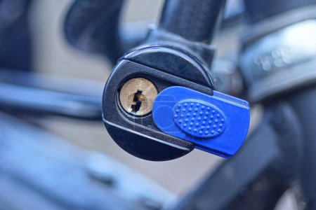 un candado de bicicleta negro con un cable atornillado en el marco metálico de una bicicleta deportiva