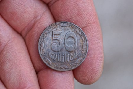 one Ukrainian brown coin lies on the fingers on the hand