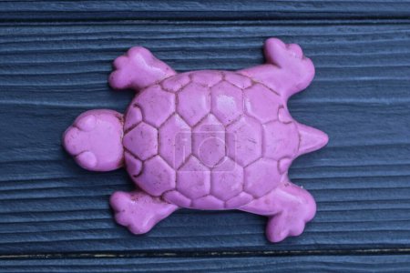 Téléchargez les photos : Une tortue jouet en plastique violet repose sur une table en bois noir - en image libre de droit