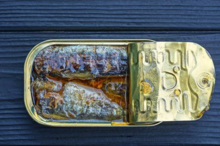 Photo for One open yellow aluminum can with sardines stands on a black wooden table - Royalty Free Image