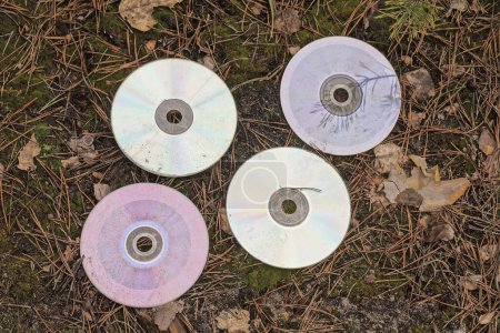 Foto de Una fila de cuatro viejos discos compactos sucios se encuentran en el suelo gris en la calle - Imagen libre de derechos