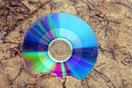 Photo for One old dirty colored compact disc lies on the brown ground in the street - Royalty Free Image