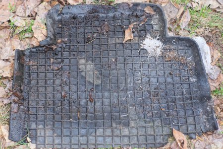una alfombra de goma sucia coche negro se encuentra en el suelo gris en la calle