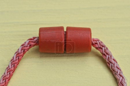 Photo for One long red shoelaces with a plastic clip lie on a yellow table - Royalty Free Image