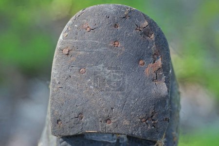 part of one old black plastic sole of a dirty boot with a heel