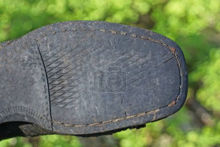 ein Stiefel mit einer alten Gummisohle mit schwarzgrauem Muster auf grünem Hintergrund