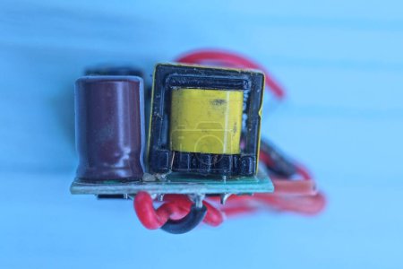 one small microcircuit with electrical parts and wires lies on blue background