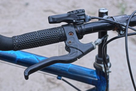 parte de un manillar de bicicleta de metal negro con freno de mano y asa de plástico en la calle