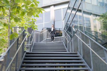 Professional woman in suit walks down steps outside a modern office building
