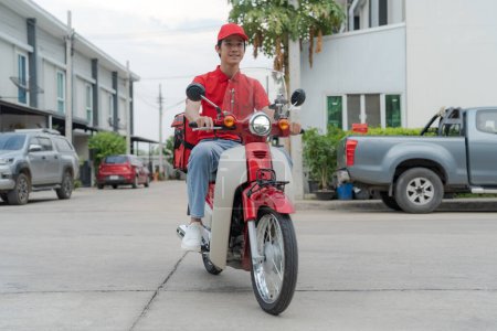 Lächelnder junger Lieferant mit roter Mütze, der auf einem umweltfreundlichen Motorrad eine urbane Straße hinunterfährt und moderne Lieferdienste und nachhaltige Lösungen für den städtischen Verkehr präsentiert