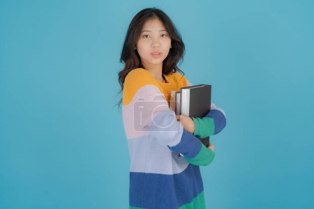 Foto de Mujer en un suéter a rayas sosteniendo una pila de libros - Imagen libre de derechos