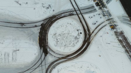 Drone photography of a roundabout and tire tracks in snow during winter cloudy day