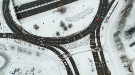 Photographie par drone d'une rue à voies multiples dans une ville allant à un rond-point pendant la journée nuageuse d'hiver