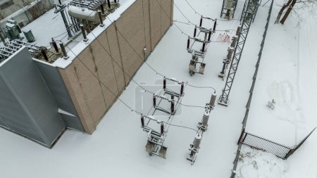 Photographie par drone d'une sous-station électrique recouverte de neige pendant la journée nuageuse d'hiver