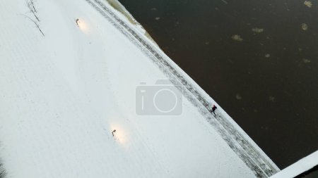 Drone photography of runner by the river exercising during winter cloudy day