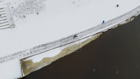 Drone photography of cyclist and runner by the river exercising during winter cloudy day
