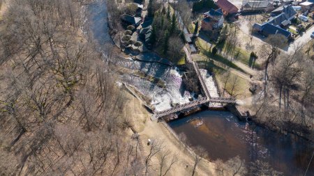 Photographie par drone d'un petit barrage, d'une cascade et d'un pont au-dessus pendant la journée ensoleillée du printemps
