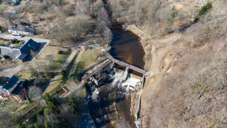 Photographie par drone d'un petit barrage, d'une cascade et d'un pont au-dessus pendant la journée ensoleillée du printemps