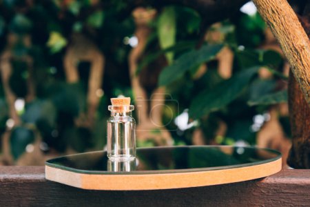 Foto de Frasco de vidrio vacío en miniatura con tapón de corcho sobre un fondo natural. Concepto moderno de boticario - Imagen libre de derechos
