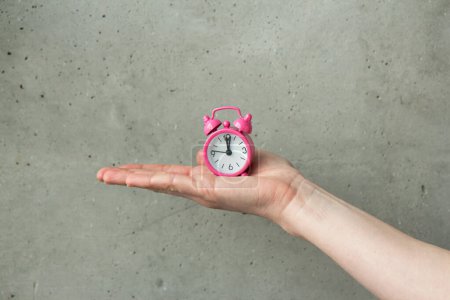 Téléchargez les photos : Pink alarm clock in female hands. Time is in our hands. Time concept, time is money - en image libre de droit