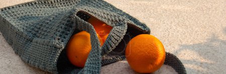 Téléchargez les photos : Sac tricoté gris à la main et oranges mûres à l'extérieur. Achats durables. Bannière - en image libre de droit