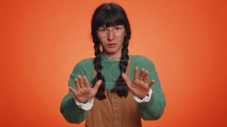 Photo for Hey you, be careful. Young nerd woman warning with admonishing finger gesture, saying no, be careful, scolding and giving advice to avoid danger, disapproval sign. Latin girl on orange wall background - Royalty Free Image