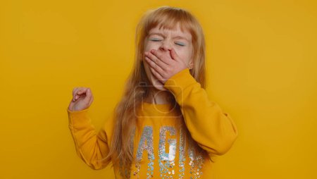 Photo for Young preteen child girl kid yawning, sleepy inattentive feeling somnolent lazy bored gaping suffering from lack of sleep. Boredom. Little toddler children tired from education on yellow background - Royalty Free Image