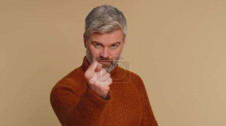 Photo for Angry aggressive middle-aged man showing fig negative gesture, you dont get it anyway. Rapacious, avaricious, acquisitive. Body language. Refusal fig sign. Greedy avaricious guy on beige background - Royalty Free Image