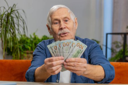 Photo for Planning family budget. Happy senior man counting money cash calculate domestic bills at home. Elderly old grandfather satisfied of income salary pension and saves money for planned vacation gifts - Royalty Free Image
